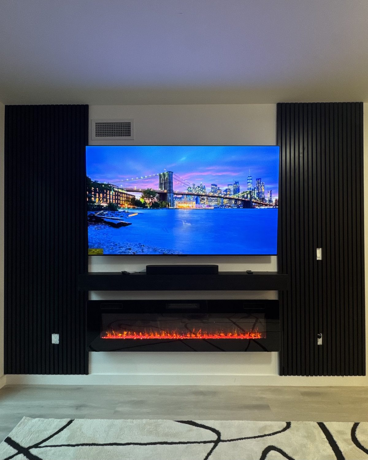The Columns, two vertical black slat columns flanking a mounted TV by SEIN ME
